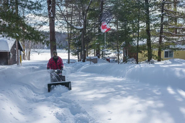 Ένας άνδρας στην εργασία ρούχα, καπέλο και γάντια, λειτουργεί ένα εκχιονιστικό / φυσητήρας μιας χειμερινής μέρας στον Καναδά. — Φωτογραφία Αρχείου
