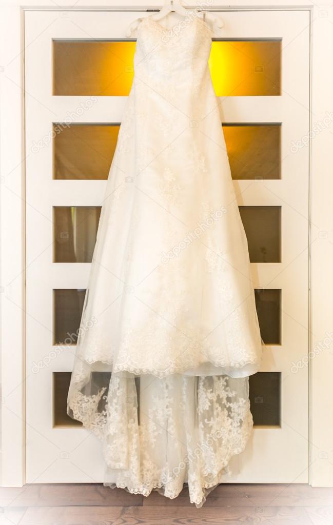 vestido de boda colgado en una puerta de luz de la habitación
