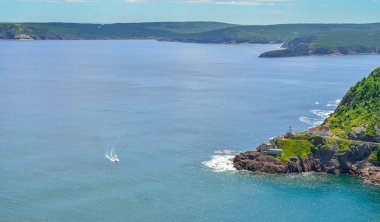 Engebeli kıyı şeridi ve Atlantik Okyanusu. Ağustos'ta sıcak yaz günü. St John's tarihi ünlü Signal Hill tepesinden manzarası. Geçen bir sürat teknesi enginliğe göre yavaş görünür..
