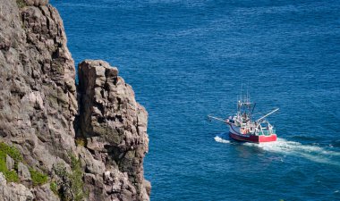 Parlak kırmızı balık tutma botu başları dışarı denize gün güneşli yaz St John's liman Newfoundland, Canada. 
