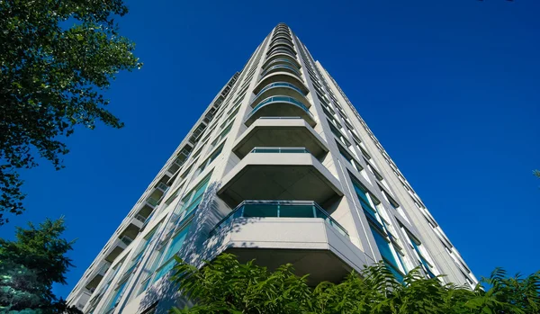 Condominium apartment building rising up into blue summer sky. — Stock Photo, Image