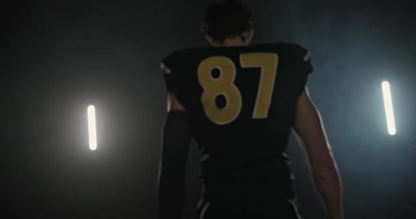 Tracking shot del giocatore di football americano che cammina su uno sfondo astratto di fumo nero — Video Stock