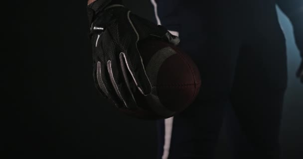 American football sportsman player holding a ball on black background close up — Stock Video