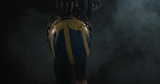 American-Football-Sportler mit Helm in der Hand auf schwarzem Hintergrund — Stockvideo