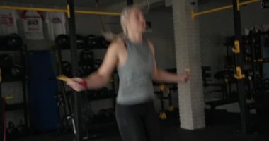 Sporcu kadın spor salonunda iple atlıyor.