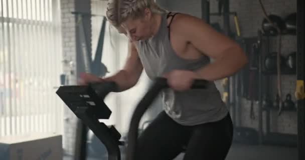 Spor salonundaki yoğun fitness antrenmanı sırasında ağır nefes alan kaslı sporcu kadın ve adım makinesi üzerinde egzersiz yapıyor. — Stok video
