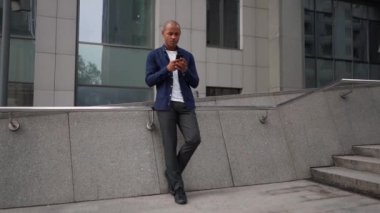 Yakışıklı genç iş adamı mutlu gülümseyen uygulamayı kullanarak mesaj atıyor..