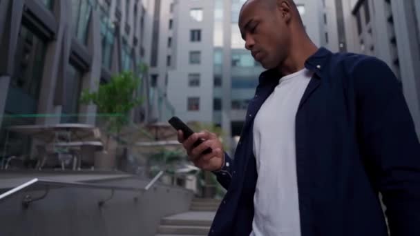 Hombre étnico usando teléfono inteligente en la calle — Vídeo de stock