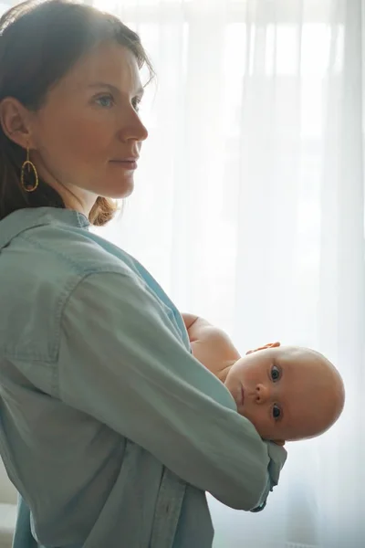 Moeder met baby staat thuis Stockfoto