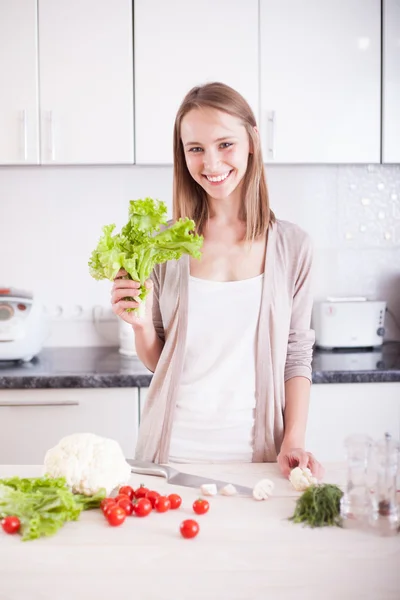 Smiling young woman standing in kitchen , holding bright green s — Stock Photo, Image