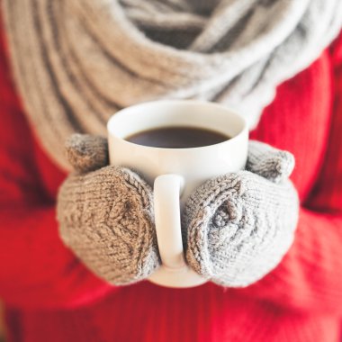 Bir kupa kahve ile holding deniz mavisi eldiven eller kadın.