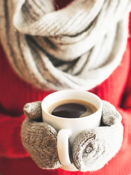 Mulher mãos em luvas de chá segurando uma caneca com café quente . — Fotografia de Stock