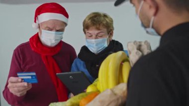 Aile, kurye tarafından sipariş edilen Xmas alışverişi için kredi kartıyla ödeme yapıyor..