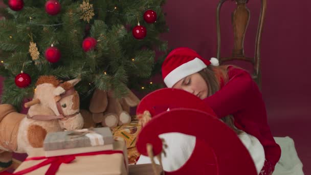Het meisje is verdrietig bij de kerstboom, maar er verscheen een slee met geschenken. Verrassing. — Stockvideo