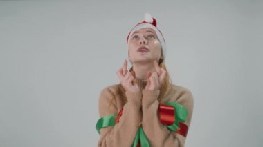 Parmakları çapraz dua eden bir kız. Xmas gümüş bir arka planda arzu ediyor.