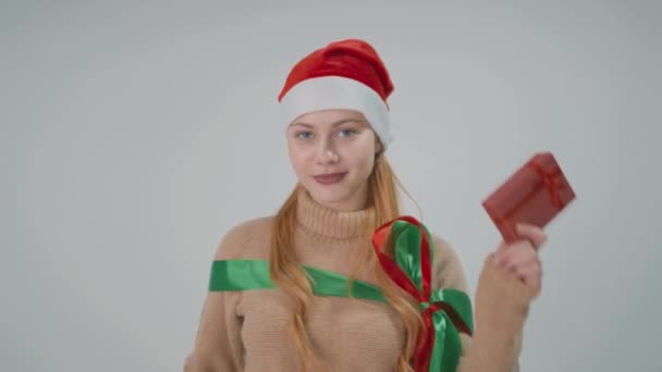 Šťastná dívka v klobouku Santa Claus s dárkovými krabicemi. Skákání a baví. — Stock video