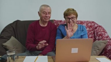 Yaşlı bir çift evde otururken videoda konuşuyor. Selamlaşmak için el sallıyorlar..