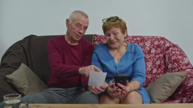 Yaşlı çift online sipariş ürünleri için kredi kartıyla ödeme yapıyor. Salgın, çevrimiçi dağıtım kavramı.