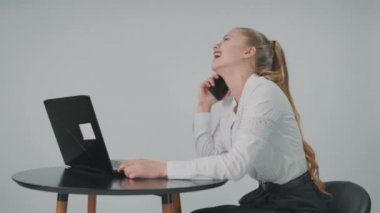 İş kadını cep telefonuyla konuşuyor ve aynı zamanda bilgisayar başında da çalışıyor.. 