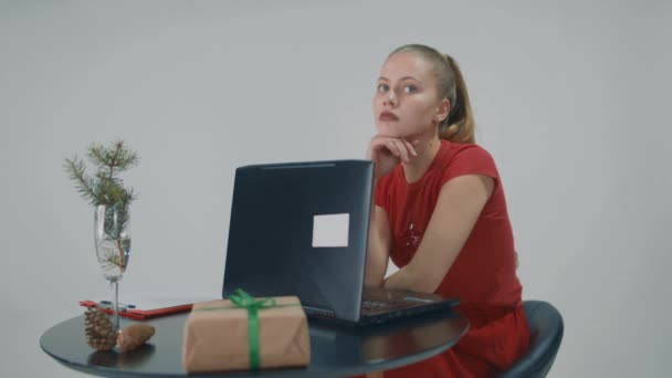 Menina bonita sentada em uma cadeira na frente do computador e ela olha pensativo. — Vídeo de Stock