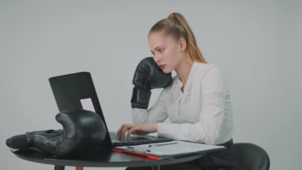 Close up de uma mulher de negócios loira em um terno vestindo luva de boxe preto e sentado no escritório. — Vídeo de Stock