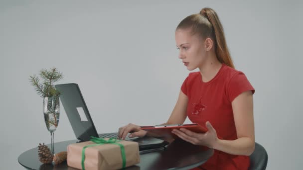 Mujer joven que trabaja en la oficina usando la computadora está chechando la lista de trabajadores. — Vídeos de Stock