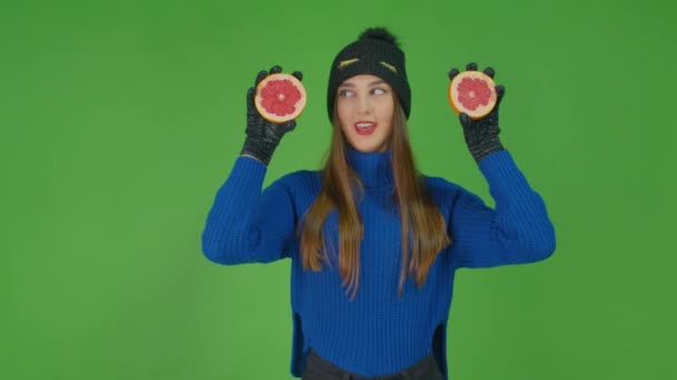 Un retrato de una atractiva mujer caucásica sonriente sosteniendo rodajas de pomelo. — Vídeo de stock