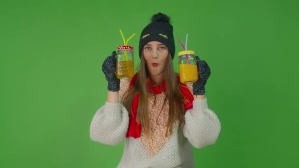 Młoda kobieta trzyma dwie szklanki pomarańczy i sok jabłkowy w ramionach z rurkami i wygląda świetnie.. — Wideo stockowe
