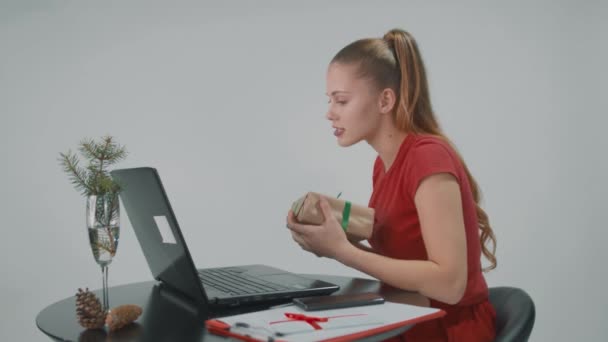 Fröhliches Mädchen in rotem Kleid, das auf einem Stuhl sitzt, bekam von einem Freund ein Geschenk für sie. — Stockvideo