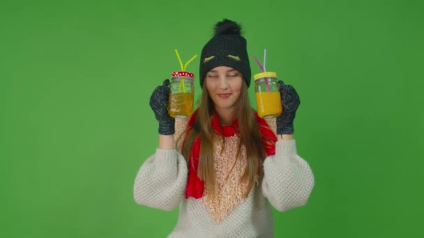 Młoda dziewczyna brzęczy szklankami soku jabłkowego i pomarańczowego z rurkami w środku. — Wideo stockowe