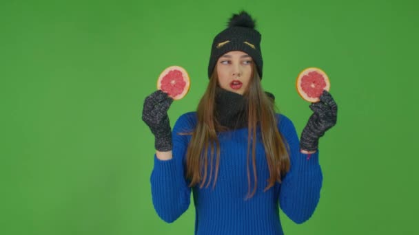 Девушка позирует с двумя ломтиками грейпфрута, глядя на них в свою очередь.. — стоковое видео