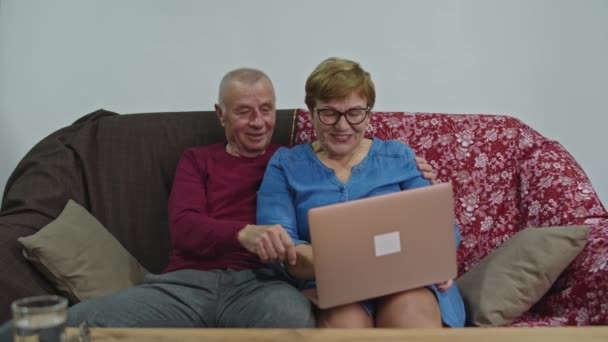 Gamla människor letar efter information i en dator och de skrattar tillsammans. — Stockvideo