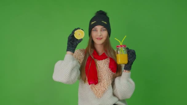 Menina com um copo de suco de limão mantendo na mão direita uma fatia de limão. Filmagem De Stock Royalty-Free