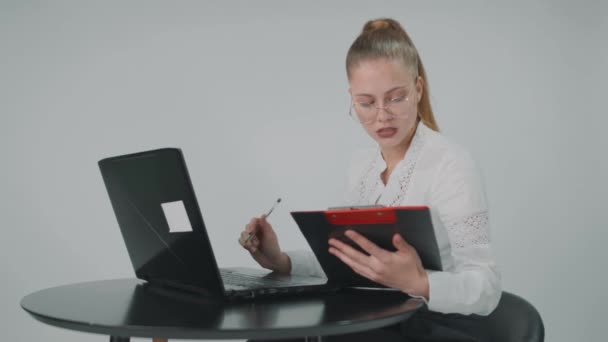 Junge Geschäftsfrau, die online mit Laptop arbeitet und Notizen macht, sitzt am Schreibtisch und bereitet Bericht vor, indem sie am Arbeitsplatz Aufsätze schreibt. — Stockvideo