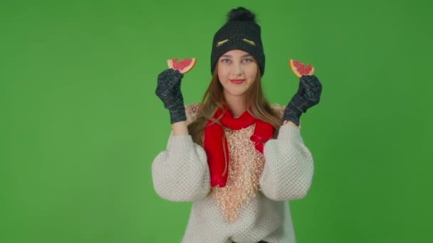 Юная леди с голубыми глазами стоит перед камерой и позирует с двумя половинками грейпфрута. — стоковое видео