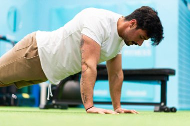 Genç yakışıklı sporcu vücut geliştirme yarışması için spor salonunda antrenman yapıyor.