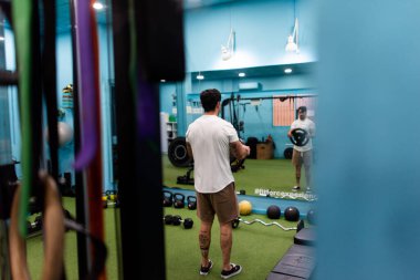 Genç yakışıklı sporcu vücut geliştirme yarışması için spor salonunda antrenman yapıyor.