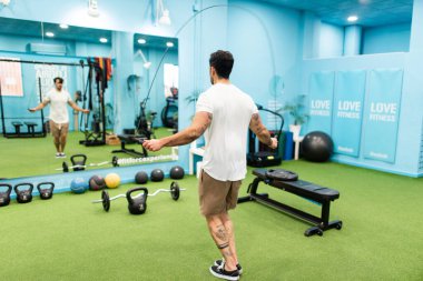 Genç yakışıklı sporcu vücut geliştirme yarışması için spor salonunda antrenman yapıyor.