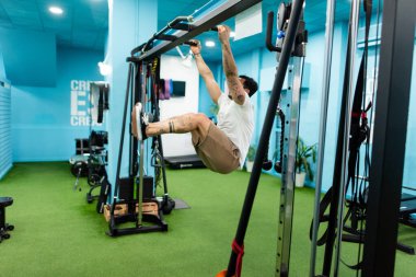 Genç yakışıklı sporcu vücut geliştirme yarışması için spor salonunda antrenman yapıyor.