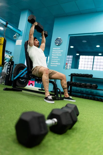 Genç yakışıklı sporcu vücut geliştirme yarışması için spor salonunda antrenman yapıyor.