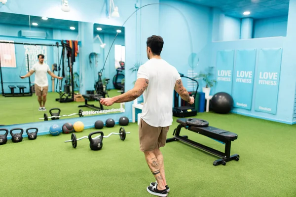 Genç yakışıklı sporcu vücut geliştirme yarışması için spor salonunda antrenman yapıyor.