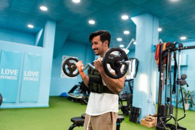 Genç yakışıklı sporcu vücut geliştirme yarışması için spor salonunda antrenman yapıyor.