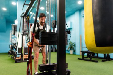 Genç yakışıklı sporcu vücut geliştirme yarışması için spor salonunda antrenman yapıyor.