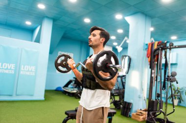 Genç yakışıklı sporcu vücut geliştirme yarışması için spor salonunda antrenman yapıyor.