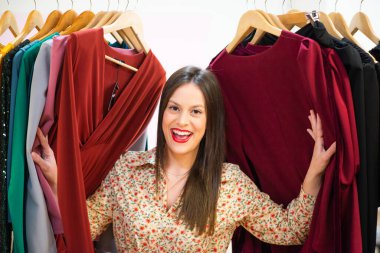 Giysileri seçen ve mağazada deneyen genç bir kız.