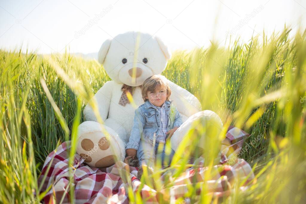 Boy playing in nature with a picnic, a teepee and a teddy bear