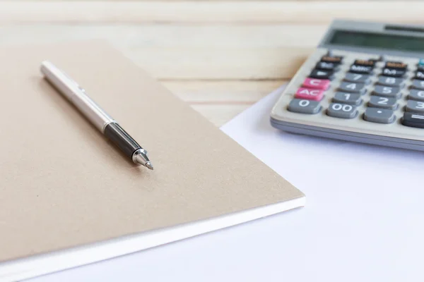 Ahşap masasında kalem olan boş beyaz bir defter. Yüzeyin derinliği