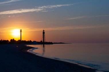 Deniz fenerleriyle güzel bir deniz doğumu. Dzharylgach Adası, Kherson Bölgesi 'ndeki deniz feneri. Ukrayna 'da deniz kıyısında eski bir deniz feneri. Dzharylgach adasında deniz fenerleriyle güzel bir deniz doğumu..