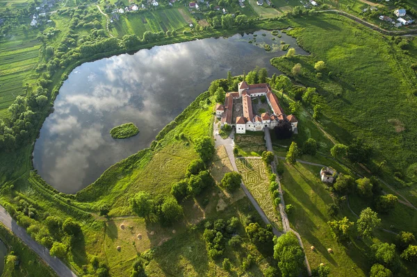 Widok z lotu ptaka wsi na stary zamek z czerwonym dachem nad jeziorem — Zdjęcie stockowe