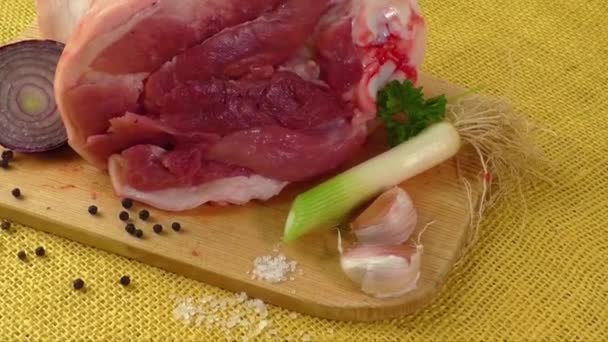 Nudillo crudo de cerdo sobre tabla de cortar de madera con ajo — Vídeos de Stock